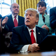 President Donald Trump signs executive orders in the Oval Office on Monday, January 30, 2016 while sycophants applaud (Photo by Andrew Harrer - Pool/Getty Images)